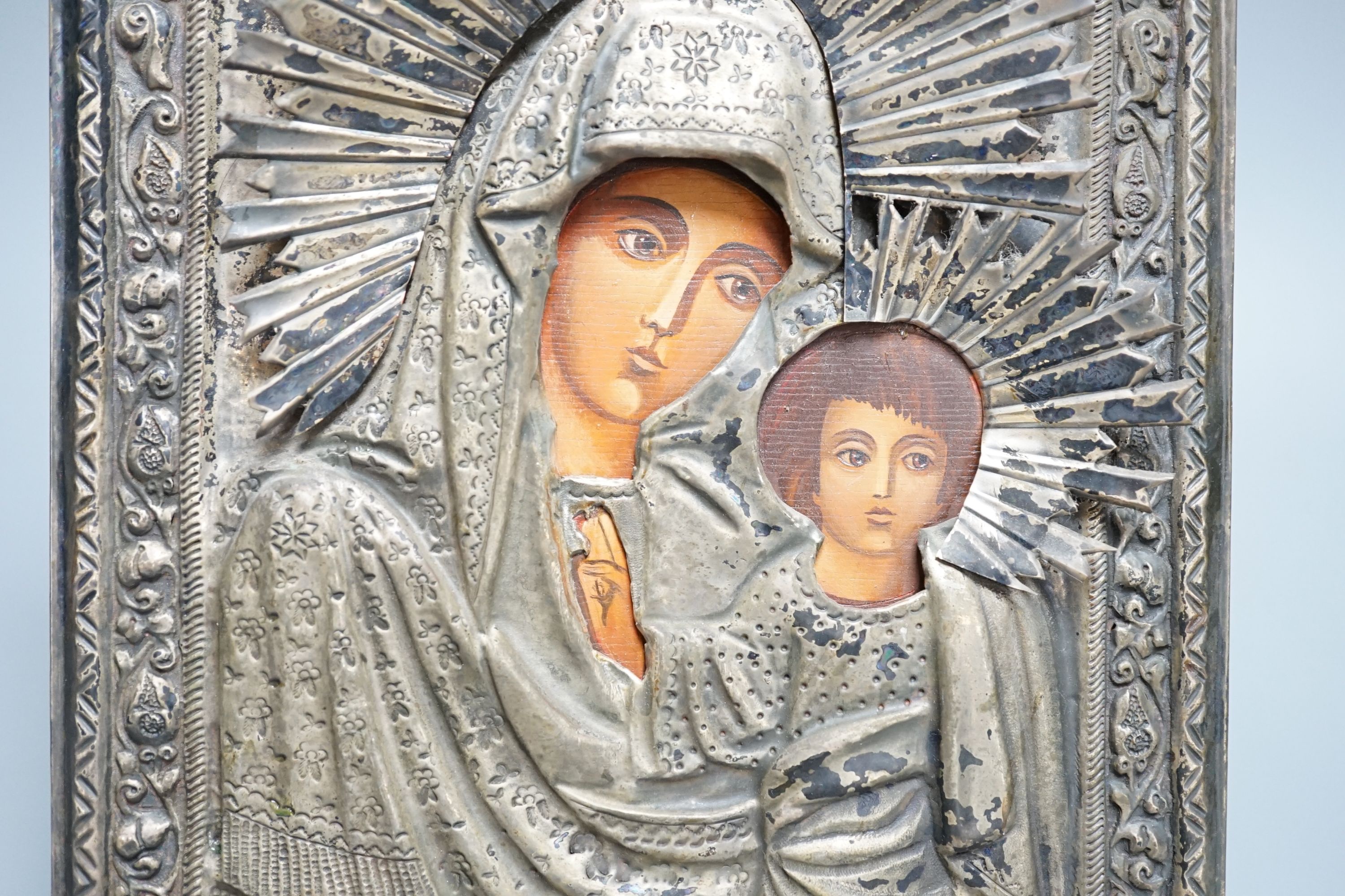 A Russian icon of Madonna and child, in embossed white metal frame, 27cm high